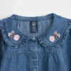 Baby-klädset i blommigt denim