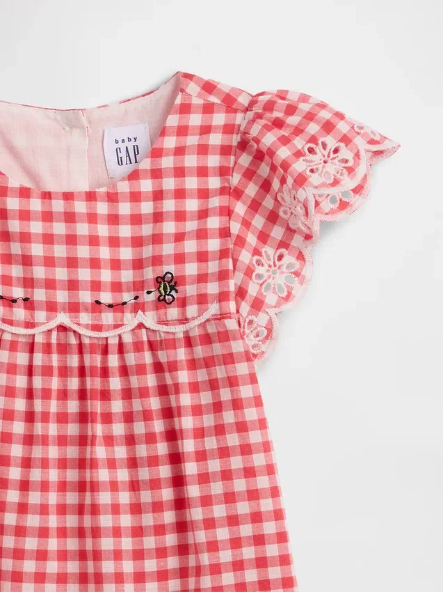 Baby-klädset i gingham med hålbroderi